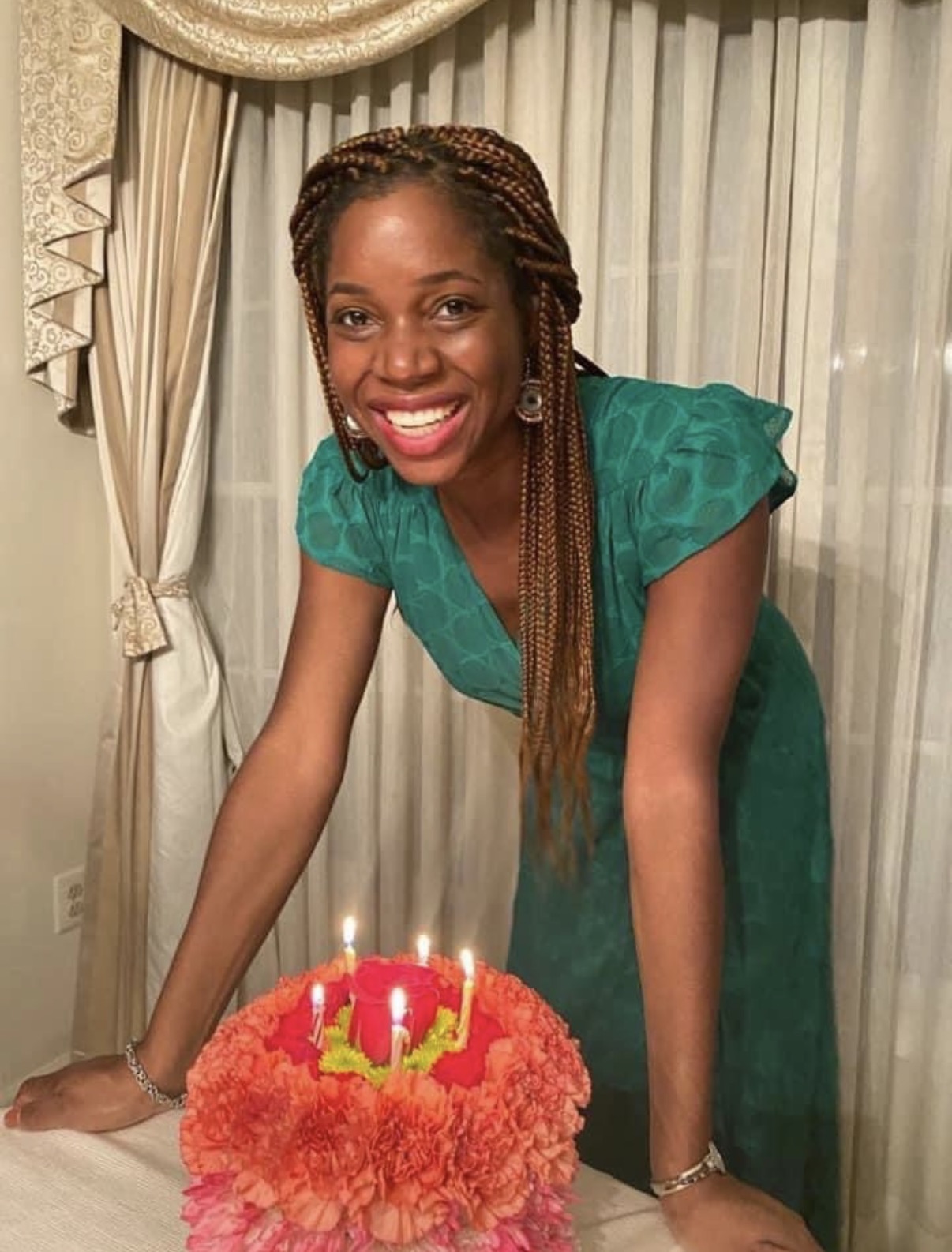 Oye smiling beside a flower-topped celebration cake.