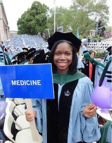 Oye in academic regalia holding a sign that reads “Medicine.”