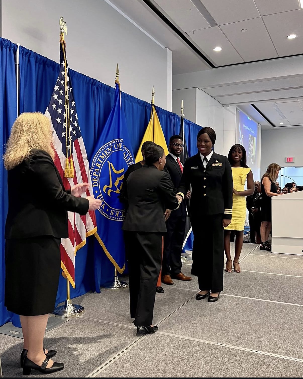 Dr. Oye E. Imoisili greeting another attendee beside U.S. Department of Health and Human Services flags