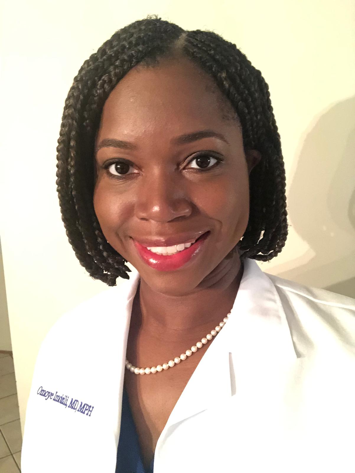 Oye smiling in a white medical coat